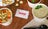 GrubHub gift card lying on table with various cups of soups around it